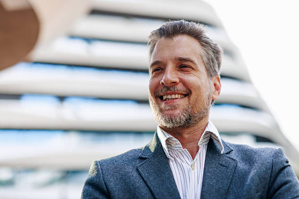 istock Smiling businessman standing in front of modern office building 2212123490