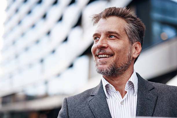 istock Smiling businessman looking up in front of modern building 2212123699