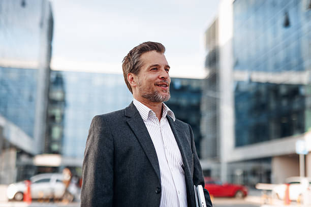 istock Confident businessman walking in a modern city with laptop in hand 2212123727