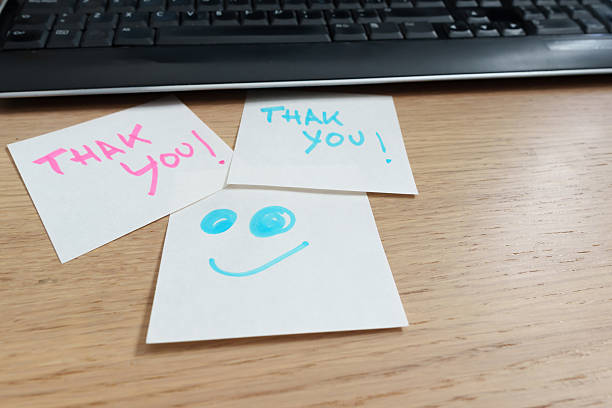 Thank you notes and a smiley face are on a desk with a keyboard, expressing gratitude and positive feedback