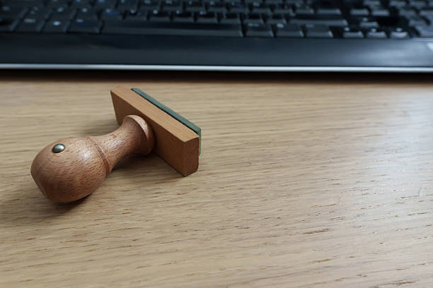 Wooden stamp placed on a desk with a computer keyboard in the background, ready for business