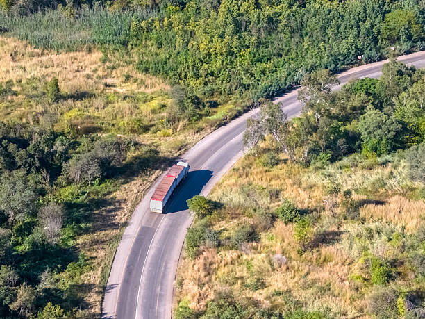 Truck and trailer seen travelling through the countryside seen from above, during autumn.