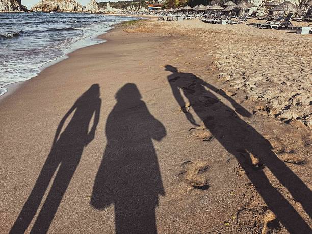 istock Shadows of Three People Walking Along a Peaceful Sandy Beach 2212130251