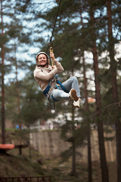 Cheerful woman rappelling from a zip line during canopy tour in nature