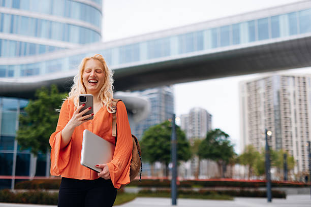 istock Young businesswoman laughing while using phone in a city 2212135405