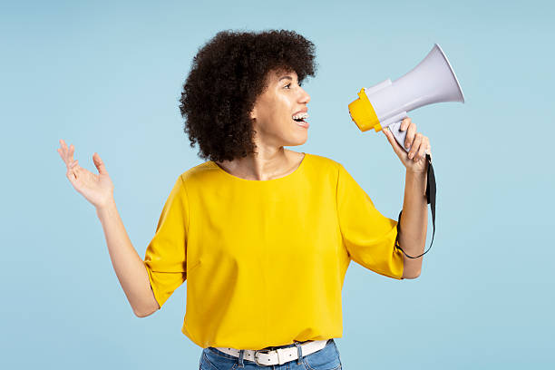 istock Young activist making an announcement using megaphone on blue background 2212140467