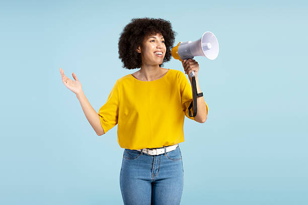 istock Young activist making an announcement with megaphone on blue background 2212140468