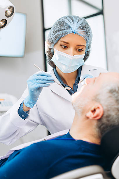 istock Female dentist using dental explorer and mirror checking the patient teeth 2212140933