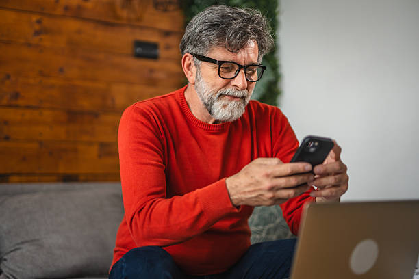 istock Modern senior man sit on sofa with laptop and use mobile phone 2212142821