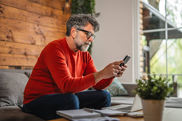 istock Modern senior man sit on sofa with laptop and use mobile phone 2212142900
