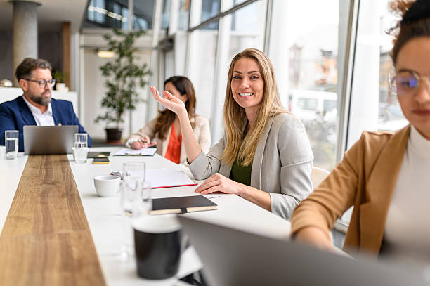 istock Confident smiling businesswoman with notepad on table collaborating with professional team in modern office 2212149583