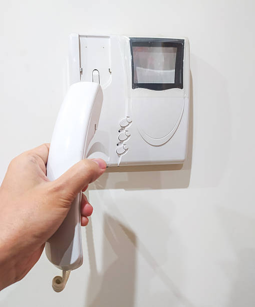 Hand holding intercom phone, security concept. Calling for assistance, receiving visitors. Use for home safety, building access, communication themes.