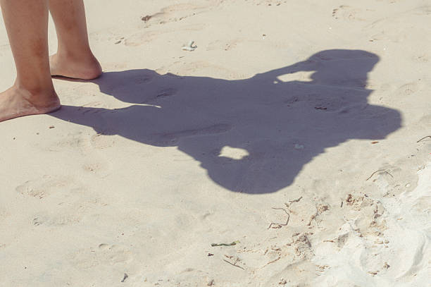Setting of feet with shadows on the beach sand