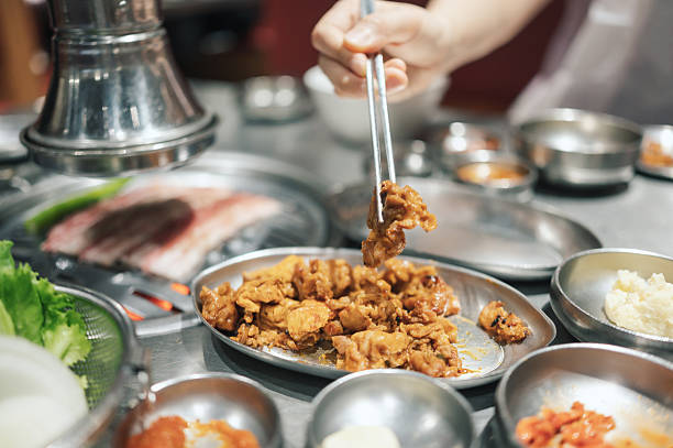 A close-up shot of succulent pork belly sizzling on a grill, surrounded by an array of classic Korean side dishes. The vibrant atmosphere captures the essence of a Korean barbecue feast, highlighting the cultural joy of communal dining.