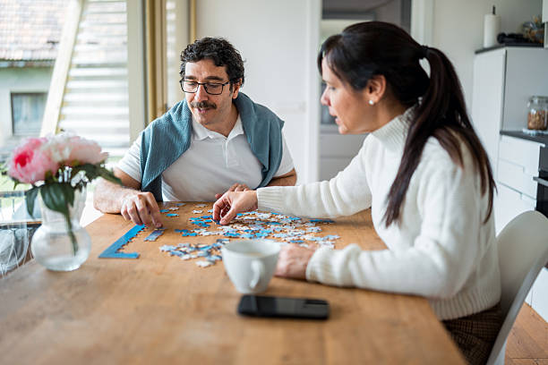 istock Cheerful Hispanic Couple Solving Puzzle Together in Cozy Mobile Home with Natural Light 2212167971