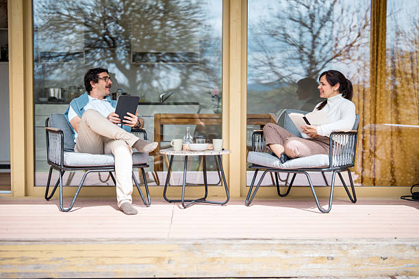 istock Hispanic Couple Relaxing On Modern Patio Chairs With Coffee And Digital Devices 2212168004