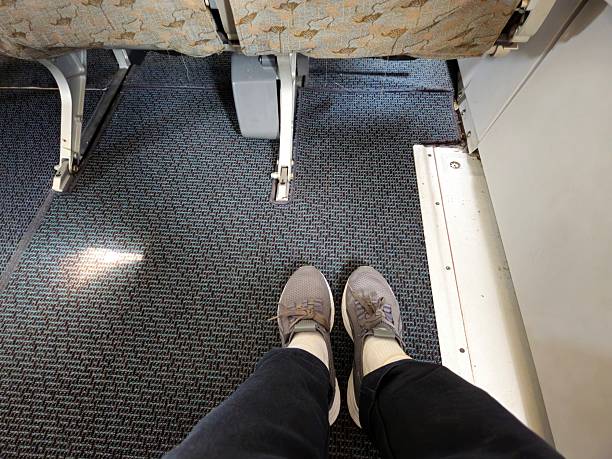 A passenger relaxes with ample legroom in an exit row seat on a commercial airplane.
