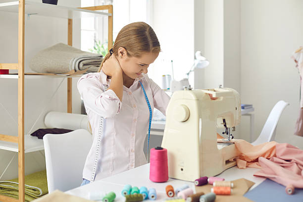 istock Woman tailor suffer from neck ache working on sewing machine 2212172082
