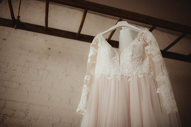 istock White lace wedding dress hanging from ladder with brick wall background 2212176074