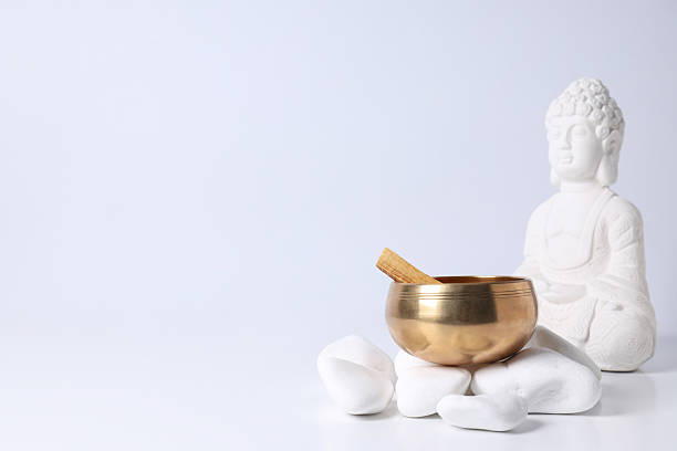 Bowl on stones and Buddha statue on white background, space for text
