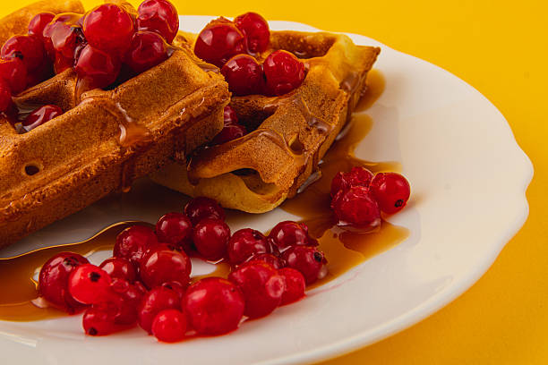 istock Delicious waffles topped with fresh red berries and syrup 2212177263