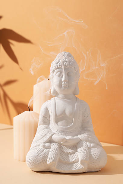 istock Buddha statue and candles on orange background 2212177292