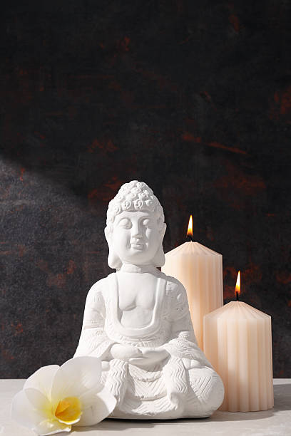 istock Buddha statue, candles and flower on dark background 2212177503