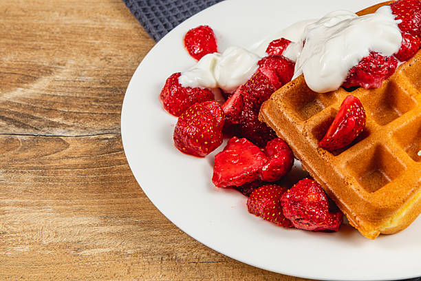 istock Delicious waffles topped with fresh strawberries and cream 2212178265