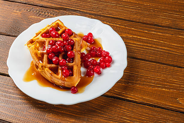 istock Delicious waffles topped with berries and syrup served 2212178338