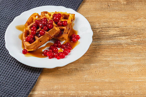istock Delicious waffles topped with berries and syrup on plate 2212178721