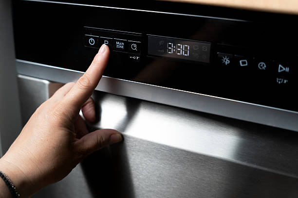 istock Close-up of a woman's hand selecting a dishwashing program on a dark panel of a dishwasher. 2212180900