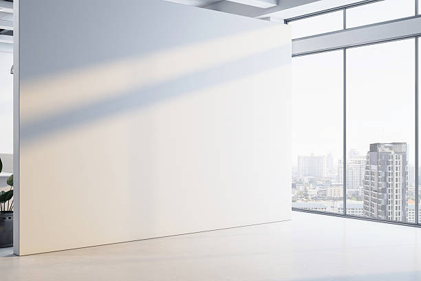 istock Blank white wall in modern office interior with city view through large glass windows, perfect for poster or logo mockup display concept.. 3D Rendering 2212182878