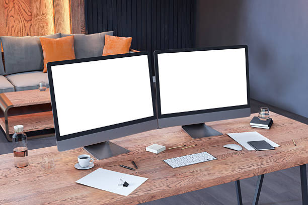 Dual blank computer monitors on wooden desk in modern office interior with sofa and ambient lighting for workspace mockup and presentation template. 3D Rendering