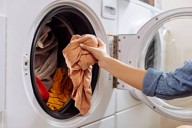 istock Close up of hand putting laundry into washing machine 2212186373