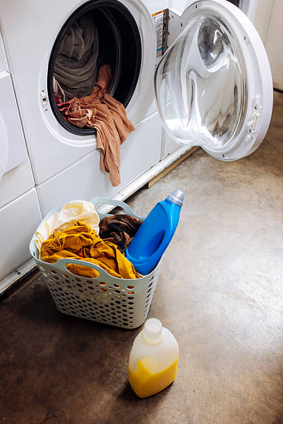 istock Washing machine with laundry and basket near it 2212186683