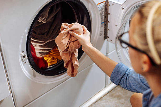 istock Woman putting clothes for washing into a washer 2212186845