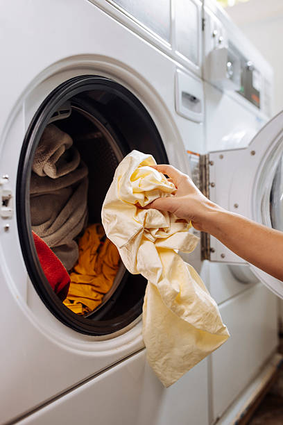 istock Close up of hand putting clothes into washer 2212186859