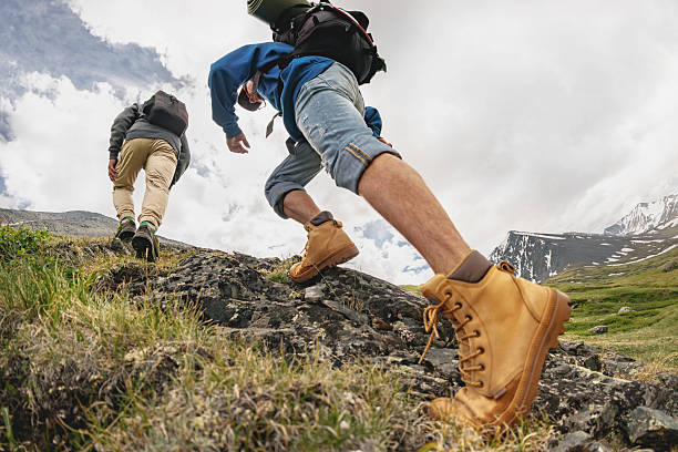 Two hikers with backpacks walks uphill in mountains