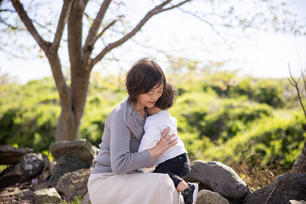 Grandmother holding her grandson under cherry tree