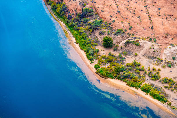 Stunning vibrant aerial view of the Colorado River winding through the Grand Canyon in Arizona, showcasing vibrant blue waters, lush green riverbanks, and rugged desert terrain. This breathtaking perspective highlights the beauty of nature’s contrast in the Southwest.