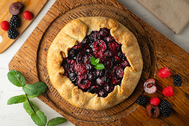 Galette tart with red berries, cherries, raspberries and blackberries. Top view table with christmas decoration.