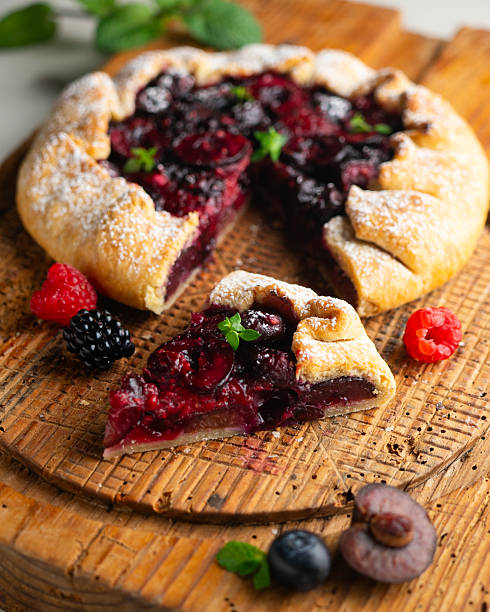 Galette tart with red berries, cherries, raspberries and blackberries. Top view table with christmas decoration..