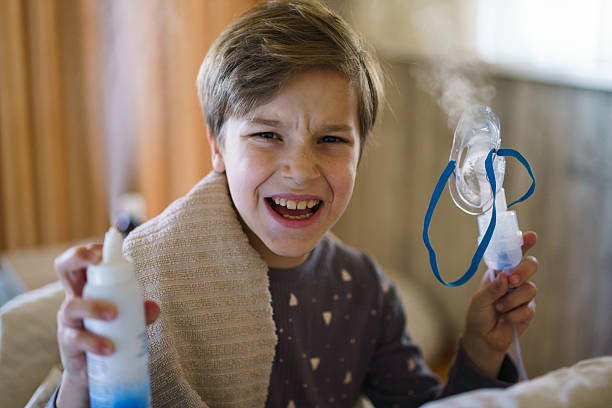 istock Sick boy holding nebulizer at home 2212194437