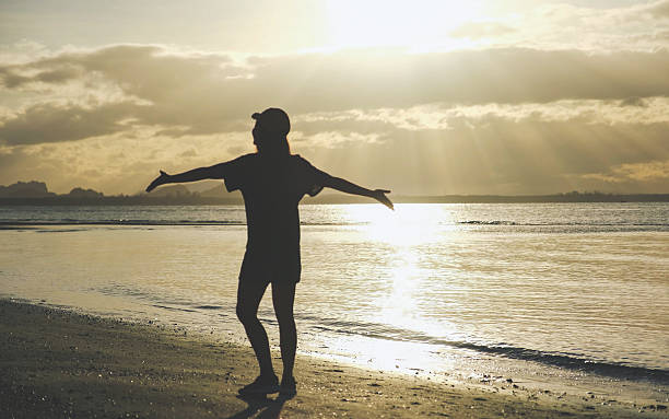 istock Silhouette of a woman open arms while strolling on the beach 2212196139