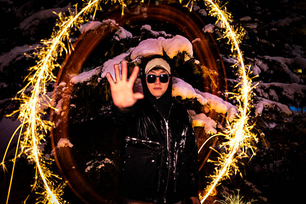 A man stands in the snow, surrounded by a long-exposure halo created with sparklers, presenting a creative and dreamy scene