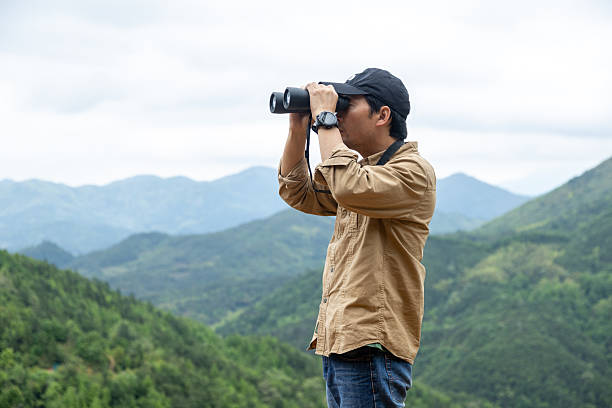 istock Man watching birds using binoculars on top of mountain 2212198853