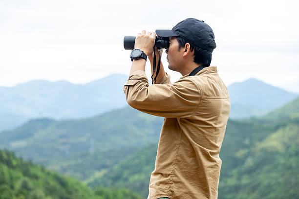 istock Man watching birds using binoculars on top of mountain 2212198883