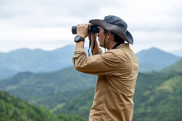 istock Man watching birds using binoculars on top of mountain 2212198888