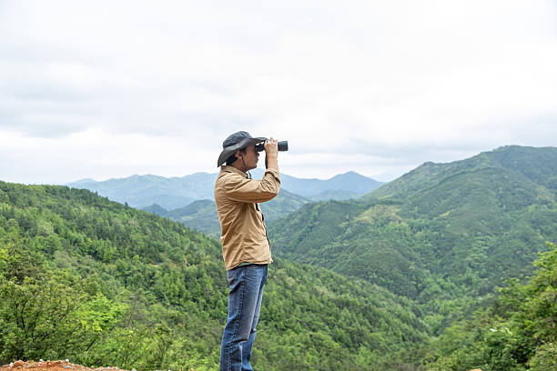 istock Man watching birds using binoculars on top of mountain 2212198898