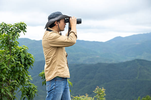 istock Man watching birds using binoculars on top of mountain 2212198944